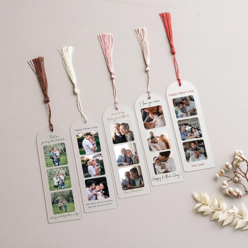 a collection of five white tassel bookmarks, each with a photo of a family, arranged on a light-colored surface. The bookmarks are designed to be used as reading aids, with each page featuring a different family photo. The bookmarks are accompanied by a small branch of white flowers, adding a touch of natural beauty to the scene.