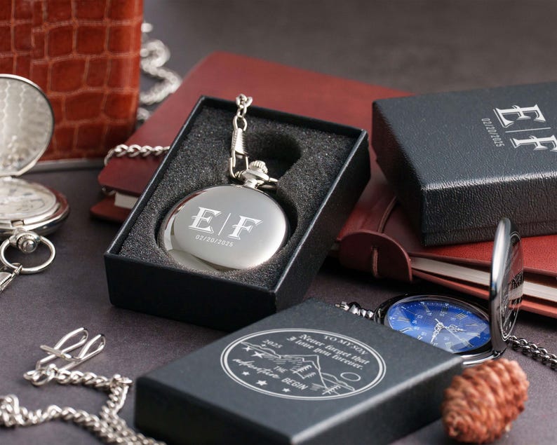 a collection of various items, including a silver pocket watch, a black box, and a blue pocket watch, all placed on a surface.