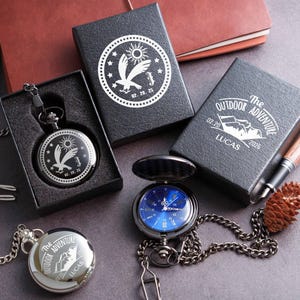 a collection of outdoor adventure-themed items, including a pocket watch, a notebook, a pen, and a pine cone.