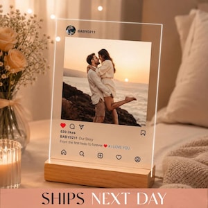May include: A clear acrylic plaque with a wooden base featuring a printed social media interface design. The center displays a photograph of a couple embracing by the ocean at sunset. Text includes BABY0211, Our Story, From the first hello to forever, and # I LOVE YOU.