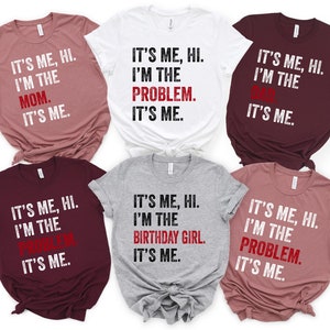 May include: Six t-shirts with the text "It's me, hi. I'm the [role]. It's me." The roles are Mom, Problem, Dad, Problem, Birthday Girl, and Problem. The shirts are in various colors, including maroon, gray, and pink.