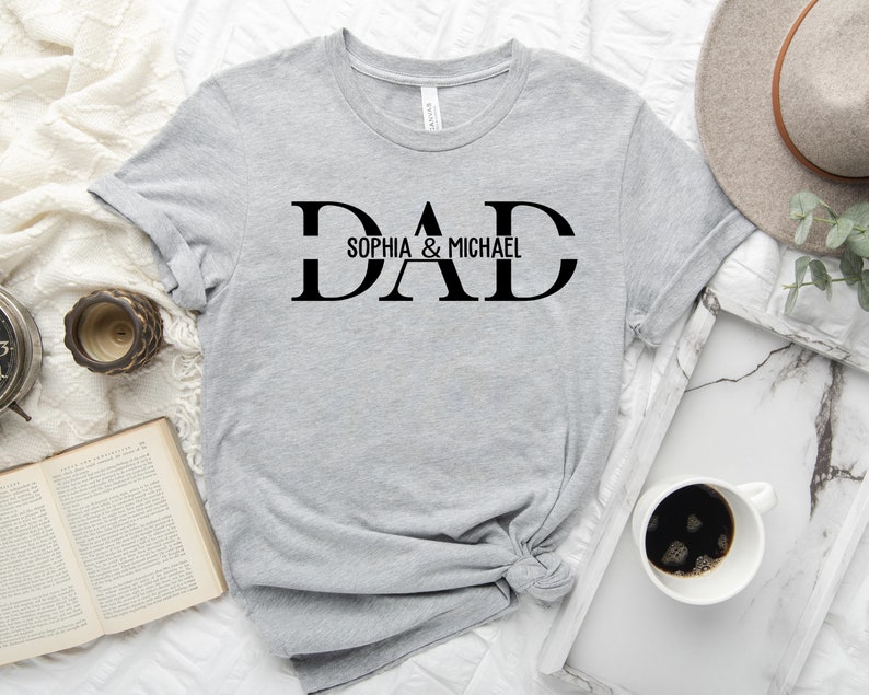 Puede incluir: Camiseta gris con texto negro que dice "DAD" con "Sophia & Michael" debajo.
