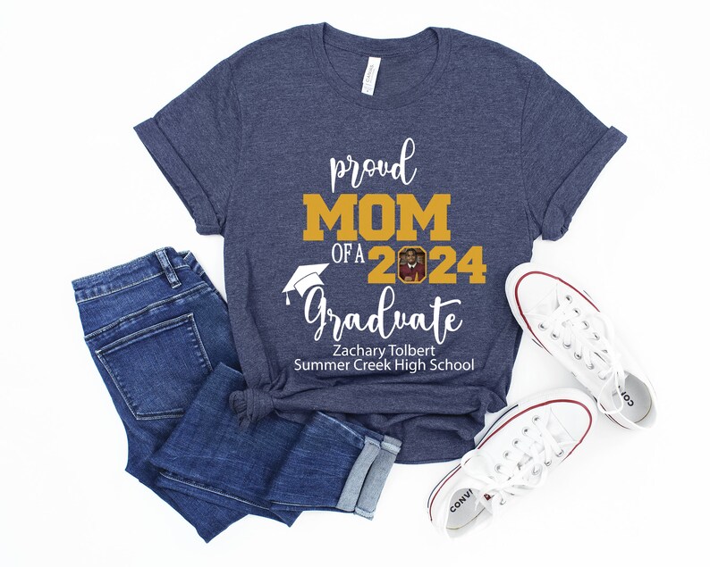 Peut inclure: Un t-shirt bleu marine avec le texte "proud MOM of a 2024 Graduate" en blanc. Le texte "MOM" est en or. Un bonnet de graduation est au-dessus du texte "Graduate". Une photo d'un dipl&ocirc;m&eacute; est dans le nombre "2024". Le texte "Zachary Tolbert Summer Creek High School" est sous le texte "Graduate".