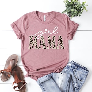 May include: A mauve t-shirt with the text "girl mama" in white lettering. The "mama" is in a leopard print pattern.