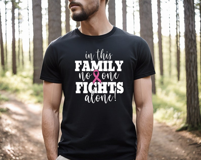 Pu&ograve; includere: Maglietta nera con una grafica bianca che recita "in this family no one fights alone!" con un simbolo di nastro rosa.