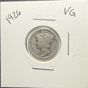 May include: A silver coin from 1926, presented in a protective holder. The coin shows a woman's profile and the inscription "IN GOD WE TRUST." The holder is marked "VG" and "1926."
