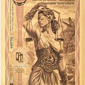 May include: A gold-toned Goldback negotiable instrument featuring an illustration of Lady Justice holding scales. The text includes "Idaho Goldback," "1/4," and "1/4000th Troy Ounce 24K Gold." The design incorporates a butterfly and the word "Justitia."