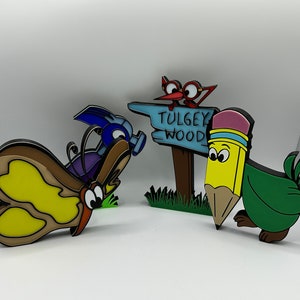 May include: A set of four colorful, cartoon-style figurines. A blue and purple butterfly, a red bird with a sign that reads "TULGEY WOOD", a green pencil with a yellow eraser, and a blue and purple bug.