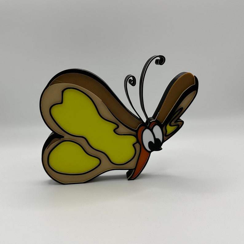May include: A brown and yellow butterfly with black outlines and large, round eyes. The butterfly has a whimsical, cartoon-like style.