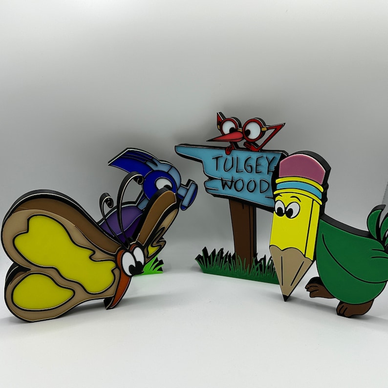May include: A set of four colorful, cartoon-style figurines. A blue and purple butterfly, a red bird with a sign that reads "TULGEY WOOD", a green pencil with a yellow eraser, and a blue and purple bug.