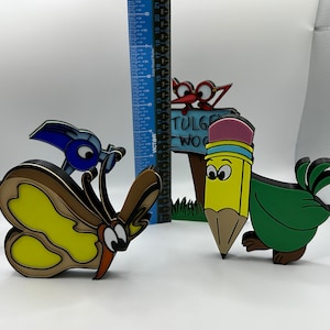 May include: A set of four colorful wooden figurines, including a butterfly, a bird, a pencil, and a sign that reads "TULGE WOOD".