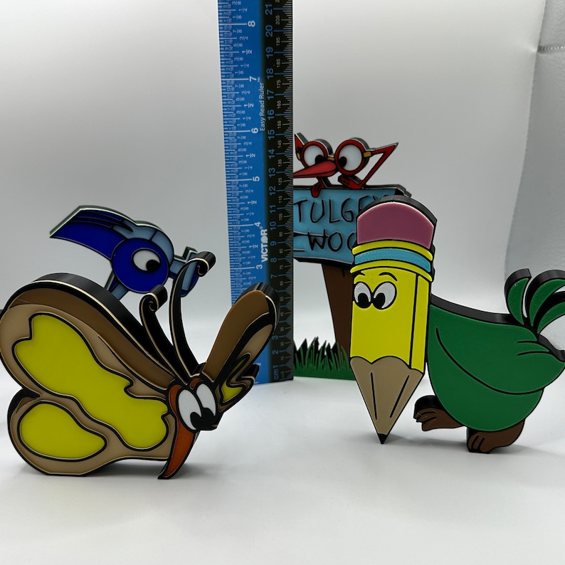 May include: A set of four colorful wooden figurines, including a butterfly, a bird, a pencil, and a sign that reads "TULGE WOOD".