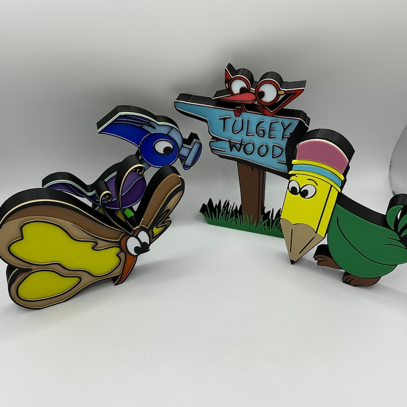 May include: A set of four colorful wooden figurines, including a butterfly, a pencil, a bird, and a sign that reads "Tulgey Wood".