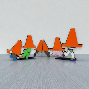 May include: A collection of colorful cartoon characters, each wearing an orange traffic cone on their head. The characters include a blue and brown figure, a green figure, a brown figure, a pink pig, and Buzz Lightyear.