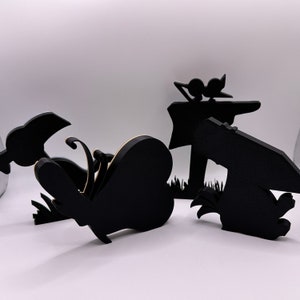 May include: A set of four black wooden silhouette decorations featuring a butterfly, a scarecrow, a bird, and a rabbit. The decorations are perfect for adding a whimsical touch to any home or garden.