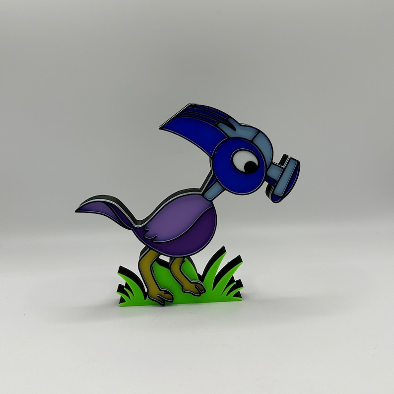 May include: A blue and purple bird figurine with a gas mask, standing on a green grass base.