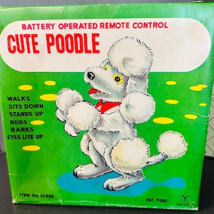 May include: A vintage box for a battery-operated remote control toy poodle. The box is green with a white oval that reads "CUTE POODLE" in red. The poodle is white with a red bow tie. The box lists the poodle's functions: walks, sits down, stands up, begs, barks, and eyes light up.