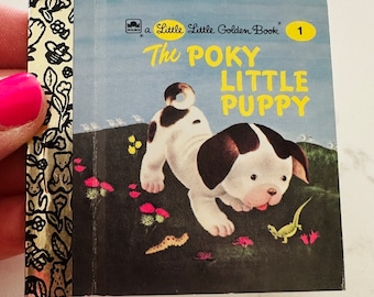 May include: A vintage Little Golden Book titled "The Poky Little Puppy." The cover features a cartoon puppy with brown and white spots, set against a green and blue background with flowers and a lizard. The book is number 1 in the series.