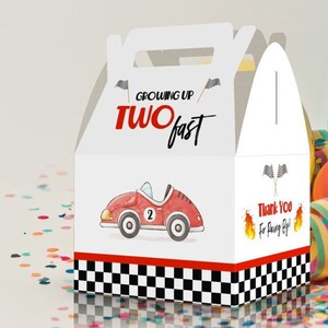 May include: White favor box with a red race car and the text "Growing Up Two Fast". The box has a checkered flag design and the text "Thank You for coming!"