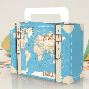 May include: A blue and brown cardboard box shaped like a vintage suitcase with a white handle. The box has a world map design and the text "First Class" and "Fragile".