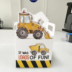 May include: A yellow construction vehicle party favor box with a yellow dump truck and the text "It was loads of fun!" printed on the front.