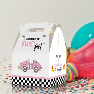 May include: White favor box with a pink race car and the text "Growing Up Two Fast". The box has a checkered pattern and pink accents.