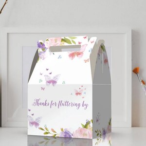 May include: White favor box with a butterfly and floral design. The box has a handle and says "Thanks for fluttering by".
