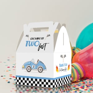 May include: A white favor box with a blue race car design. The box has a handle and says "Growing Up Two Fast" on the front. The back of the box says "Thank You for Racing By!"