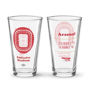Puede incluir: Dos vasos de pinta de vidrio transparente con diseños rojos y blancos del Arsenal Football Club. Un vaso presenta el contorno del Emirates Stadium y el texto "Emirates Stadium". El otro vaso presenta el texto "Arsenal", "51.5551°N 0.1084°W", y un cañón.