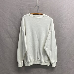 May include: A white crew neck sweatshirt with long sleeves.