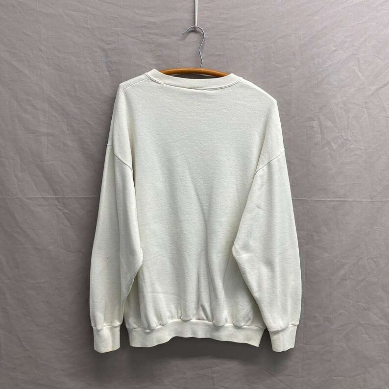 May include: A white crew neck sweatshirt with long sleeves.