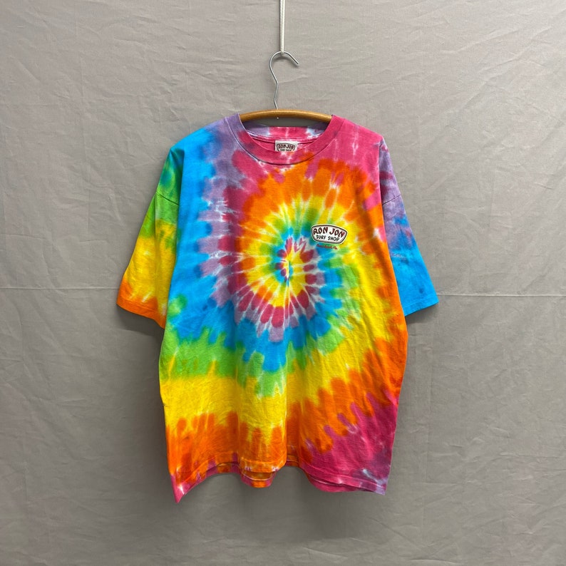 May include: A tie-dye t-shirt with a rainbow swirl pattern. The shirt has a small logo on the front that says "Ron Jon Surf Shop".