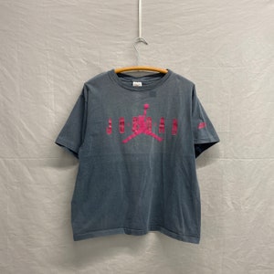 May include: A vintage grey t-shirt with a pink Jordan logo and the word "JORDAN" printed on the front.