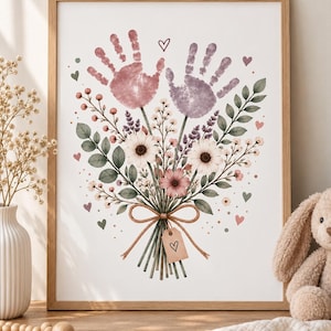 Peut inclure: Une impression d'art encadrée représentant un bouquet de fleurs où deux empreintes de mains, une rose et une violette, servent de fleurs. Les tiges sont liées par une ficelle brune et une petite étiquette rectangulaire avec un cœur dessiné.