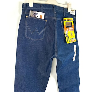May include: A pair of blue denim jeans with a back pocket and a Wrangler label. The label says "Pre-Reduced" and "Cowboy Cut" with a size 33.