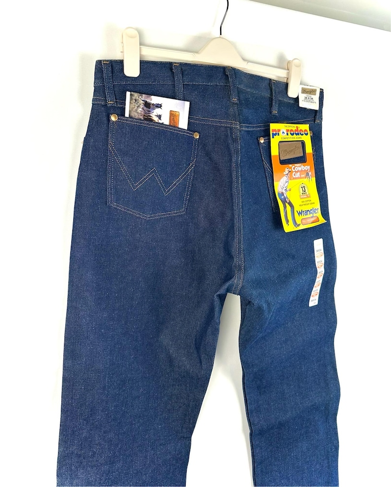 May include: A pair of blue denim jeans with a back pocket and a Wrangler label. The label says "Pre-Reduced" and "Cowboy Cut" with a size 33.