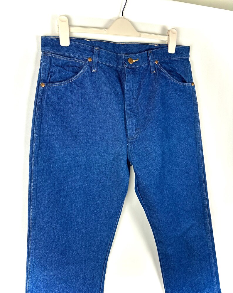 May include: A pair of blue denim jeans with a classic straight leg fit. The jeans have a button fly and five pockets.