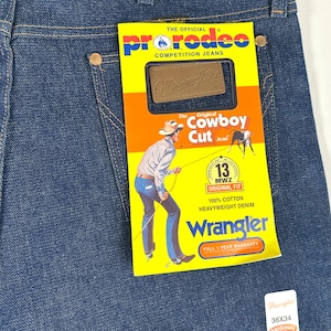 May include: A pair of blue denim jeans with a yellow and red label that says "The Official ProRodeo Competition Jeans" and "Wrangler The Original Cowboy Cut Jean". The label also features a cowboy riding a horse and a 13MWZ Original Fit logo. The jeans are size 36 x 34.