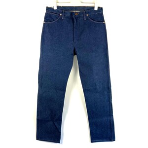 May include: A pair of dark blue denim jeans with a straight leg fit. The jeans have a classic five-pocket style and a button fly.