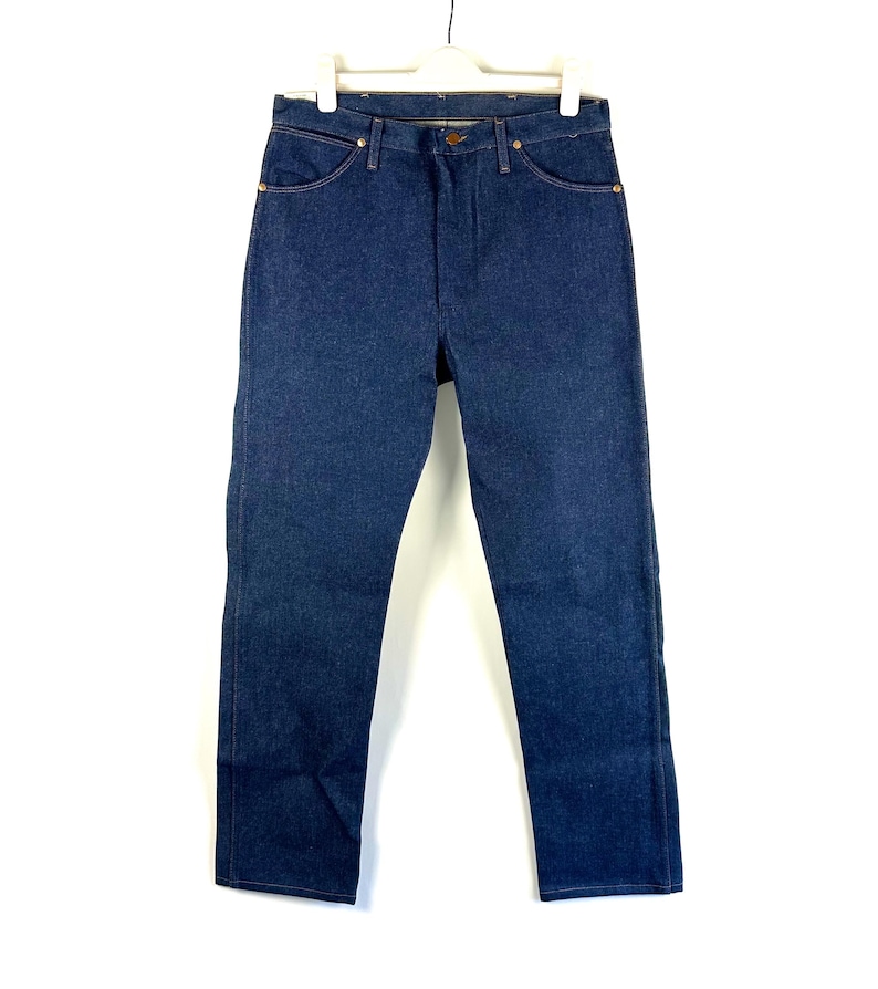 May include: A pair of dark blue denim jeans with a straight leg fit. The jeans have a classic five-pocket style and a button fly.