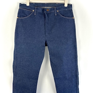 May include: A pair of dark blue denim jeans hanging on a white hanger. The jeans have a classic straight leg style and are made of a sturdy denim fabric.