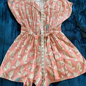 May include: A pink and white short-sleeved dress with a sailboat print. The dress has a tie at the waist and a collar.