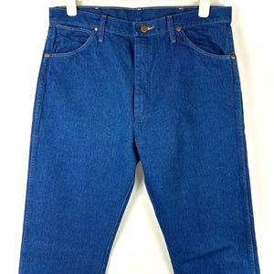 May include: A pair of blue denim jeans with a classic straight leg fit. The jeans have a button fly and five pockets.