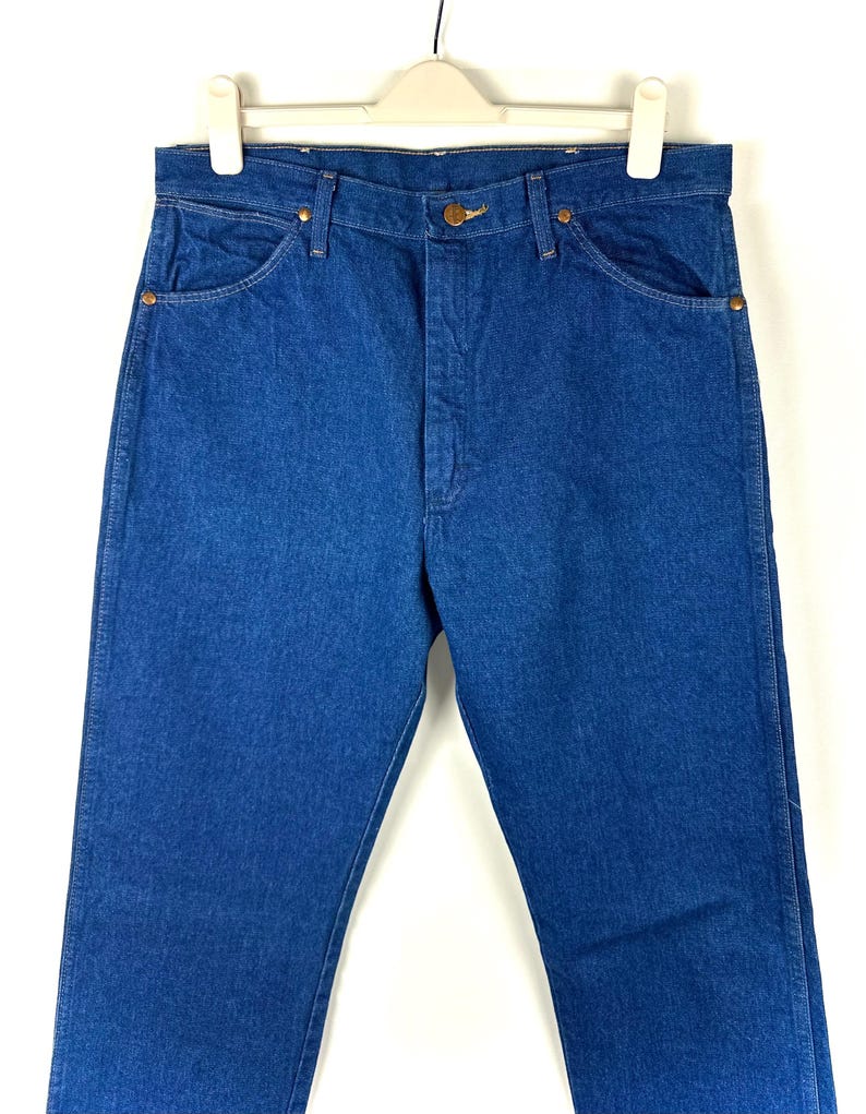 May include: A pair of blue denim jeans with a classic straight leg fit. The jeans have a button fly and five pockets.