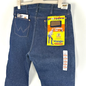 May include: A pair of blue denim jeans with a back pocket and a Wrangler label. The label says "The Official ProRodeo Competition Jeans" and "Cowboy Cut".