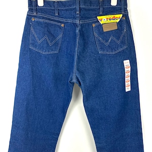May include: A pair of blue denim jeans with a yellow and red label that says "The Official Competition Jeans" and "Wrangler".