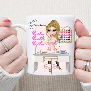 May include: White ceramic mug featuring a pink and white illustration of a woman with blonde hair giving a manicure. The mug has the text "Emma Nails Nails Nails" on it.
