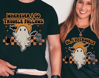 May include: Two black t-shirts with a ghost and Halloween themed graphics. The text on the shirts reads "Wherever I go Trouble Follows" and "Hi, I'm Trouble".