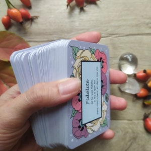 May include: A deck of cards with a floral design and the text "Fid&eacute;lit&eacute; Je te suis fid&egrave;le, il n'y a que toi dans mon coeur et dans ma vie." The cards are blue with white stars and feature a yellow rose, pink and purple flowers, and red poppies.