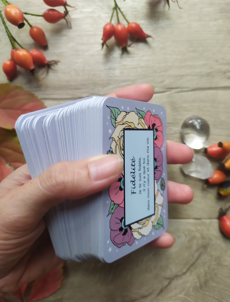 May include: A deck of cards with a floral design and the text "Fid&eacute;lit&eacute; Je te suis fid&egrave;le, il n'y a que toi dans mon coeur et dans ma vie." The cards are blue with white stars and feature a yellow rose, pink and purple flowers, and red poppies.